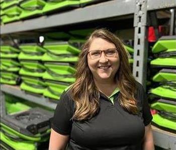 Image of female employee wearing a black shirt in front of a green background
